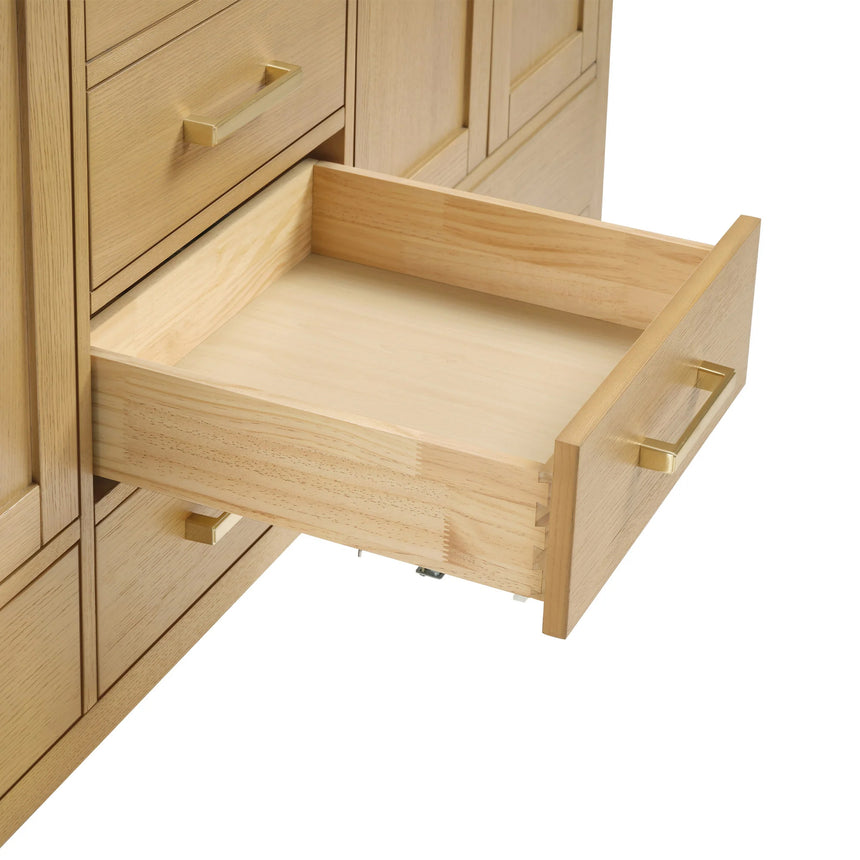 Bathroom vanity with wooden cabinets and white countertop, featuring a toilet and towel on the side.