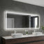 Bathroom vanity with a large illuminated mirror above two white sinks.