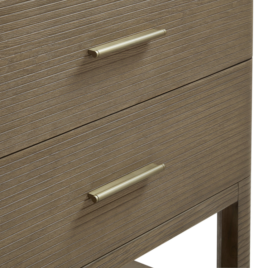 A modern bathroom vanity with a light oak wood frame, six drawers, an open lower shelf, and a white marble top with an integrated sink. The vanity is styled in a bright bathroom with a white freestanding tub, a gold faucet, and a glass shower stall in the background.