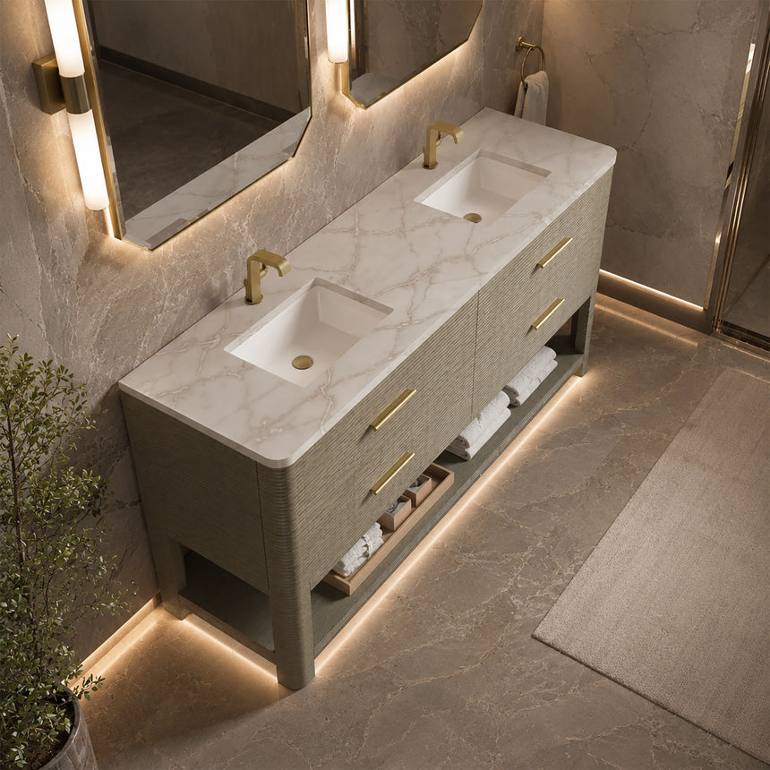 A modern bathroom vanity with a light oak wood frame, six drawers, an open lower shelf, and a white marble top with an integrated sink. The vanity is styled in a bright bathroom with a white freestanding tub, a gold faucet, and a glass shower stall in the background.