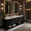 A modern double-sink bathroom vanity in a dark textured finish with gold-tone handles, set against a warm stone wall with illuminated rectangular mirrors. The scene includes a walk-in shower, marble flooring, and tasteful decor.