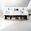 A modern wall-mounted double-sink bathroom vanity with a white countertop, two rectangular basins, black faucets, open lower storage drawers, and a large mirror above on a white wall.
