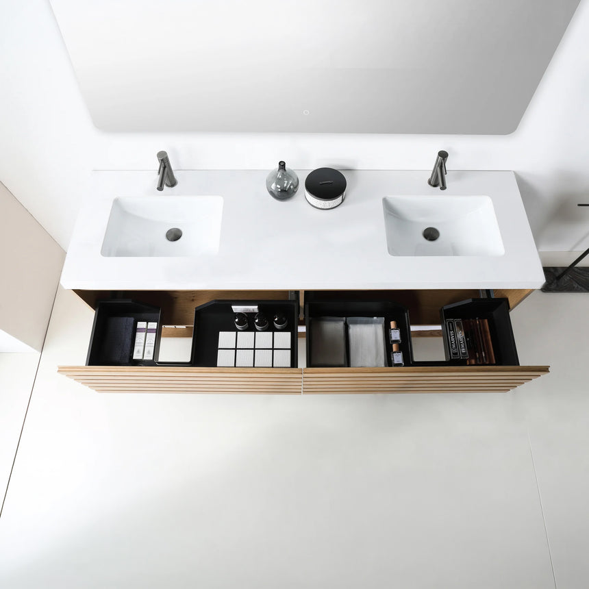 A modern floating bathroom vanity with a light oak wood finish, a white countertop, and an integrated sink, shown in a styled bathroom setting with a bathtub, shower glass, and decorative plants.