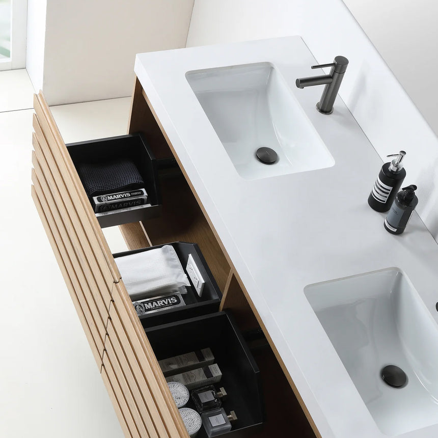 A modern floating bathroom vanity with a light oak wood finish, a white countertop, and an integrated sink, shown in a styled bathroom setting with a bathtub, shower glass, and decorative plants.