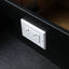 A white double electrical outlet cover plate mounted on a black wooden drawer front.