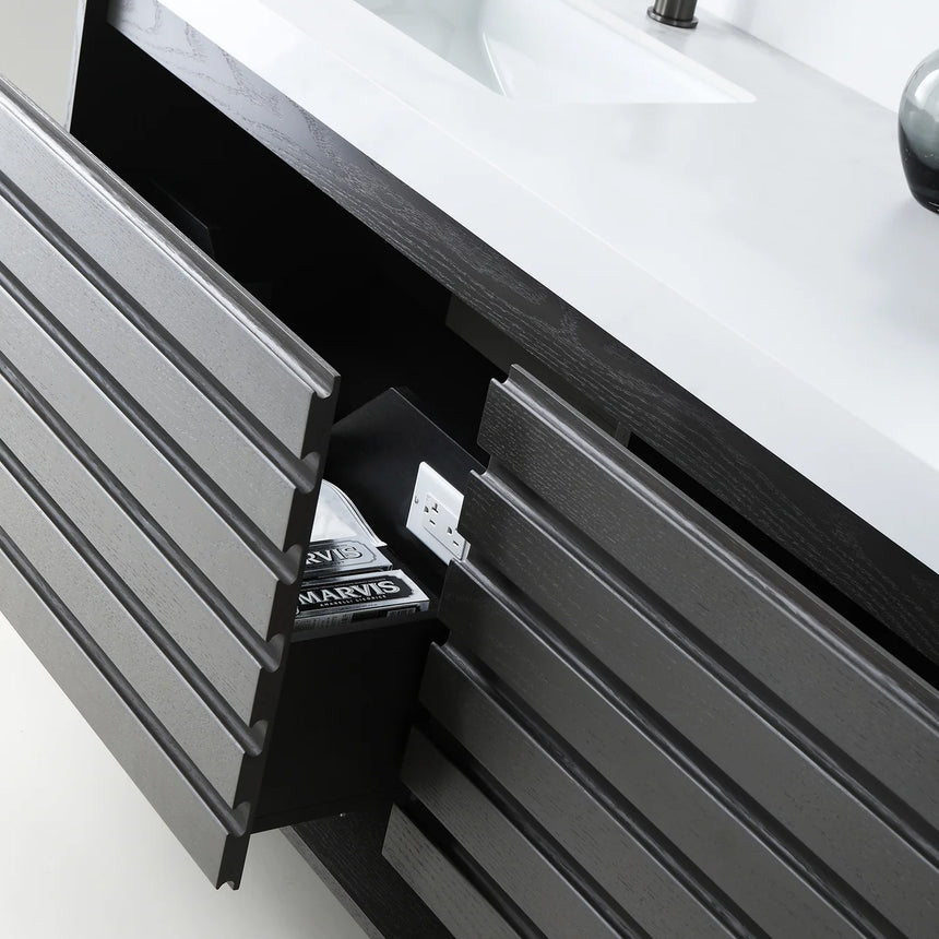A modern floating bathroom vanity with a light oak wood finish, a white countertop, and an integrated sink, shown in a styled bathroom setting with a bathtub, shower glass, and decorative plants.