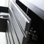 Close-up of a modern dark gray or black cabinet drawer front with a silver-toned metal pull handle, shown partially open in an interior setting.