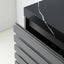 Close-up of a modern cabinet or refrigerator with dark gray slatted front drawers and a glossy black top featuring a white veined marble pattern.