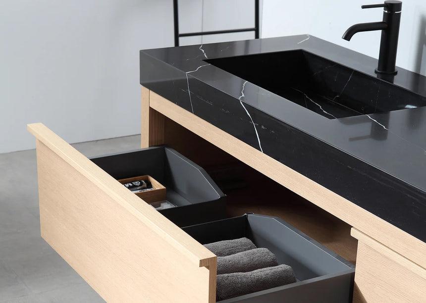 Bathroom vanity with black countertop and wooden cabinet in a bright room.