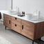 Bathroom vanity with wooden cabinets, white countertop, and two round white sinks.
