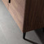 Wooden cabinet with black legs on a gray floor