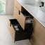 Bathroom vanity with open drawer containing toiletries, against a light-colored wall.