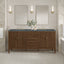 Bathroom vanity with two mirrors, lights, and decorative items against a tiled wall.