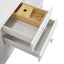 Wooden sink inside an open white cabinet with brass handles.