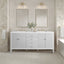Bathroom vanity with two mirrors, lights, and a bathtub in a tiled room.