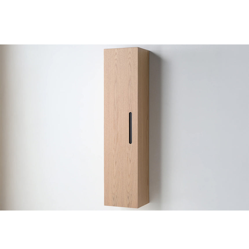A tall, narrow wall-mounted cabinet in a light natural wood finish with a slim black vertical handle, shown against a plain light gray wall.