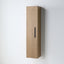 A tall, narrow wall-mounted cabinet with a light oak wood grain finish and a slim black vertical handle, shown against a plain white wall.