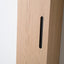 Close-up of a light oak wood cabinet door featuring a sleek, minimalist black vertical pull handle.