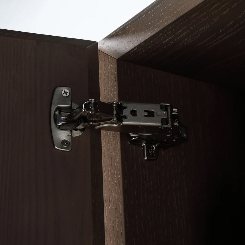 A tall, narrow wall-mounted cabinet in a light natural wood finish with a slim black vertical handle, shown against a plain light gray wall.