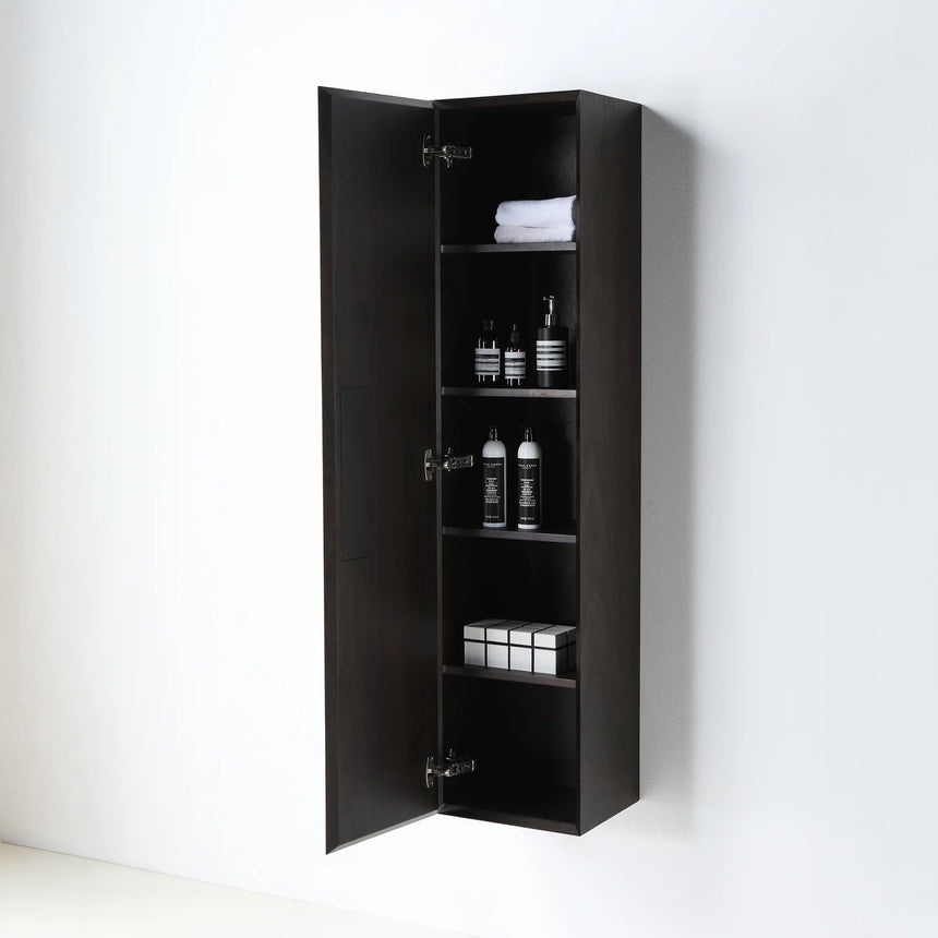 A tall, narrow wall-mounted cabinet in a light natural wood finish with a slim black vertical handle, shown against a plain light gray wall.