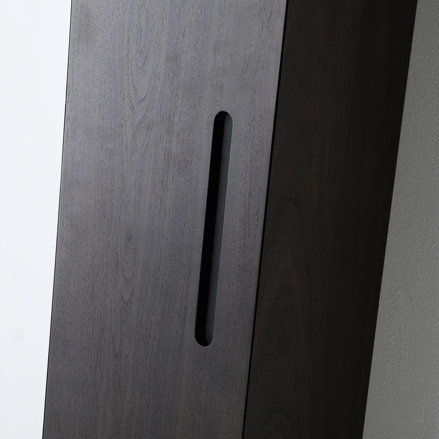 A tall, narrow wall-mounted cabinet in a light natural wood finish with a slim black vertical handle, shown against a plain light gray wall.