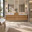 A modern double-sink bathroom vanity with light oak wood floating cabinets, white countertops, and two large backlit mirrors, shown in a bright, sunlit bathroom with a bathtub, walk-in shower, and woven rug.